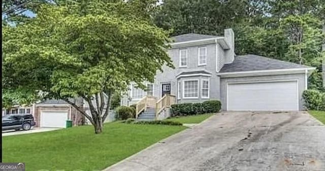 view of front of property with a front yard, driveway, a chimney, and an attached garage