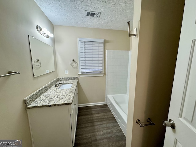 bathroom with baseboards, visible vents, wood finished floors, a textured ceiling, and vanity