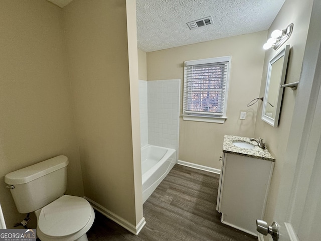 full bathroom with a textured ceiling, toilet, wood finished floors, visible vents, and baseboards