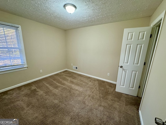 carpeted empty room featuring baseboards, visible vents, and a textured ceiling