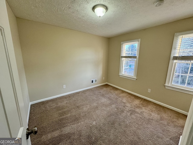 unfurnished room featuring carpet, plenty of natural light, visible vents, and baseboards