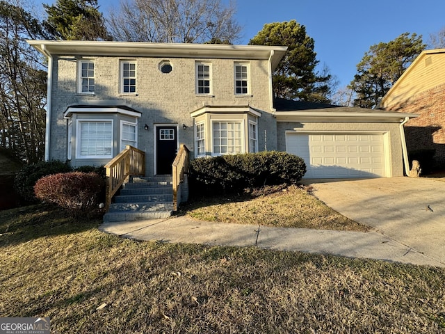 colonial home with driveway, brick siding, and an attached garage