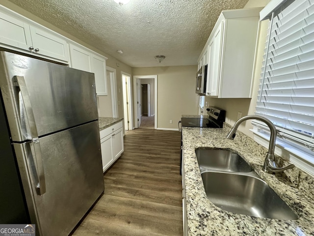 6380 Phillips Pl, Lithonia, GA 30058 - kitchen featuring appliances with stainless steel finishes, white cabinets, dark wood-style flooring, light stone counters, and a textured ceiling