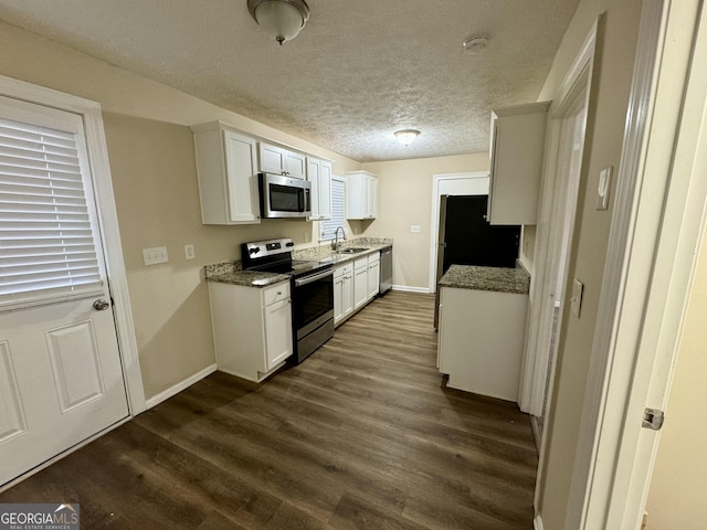 kitchen with a textured ceiling, stainless steel appliances, dark wood-type flooring, and a sink