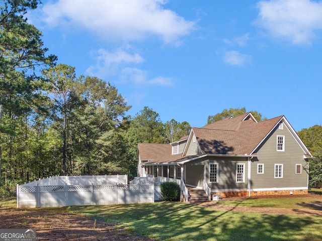 exterior space with a fenced in pool, roof with shingles, and a lawn