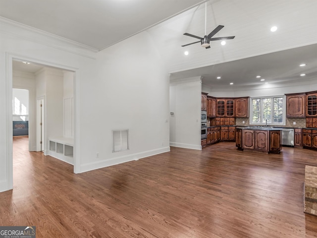 unfurnished living room with visible vents, dark wood-type flooring, ornamental molding, a sink, and baseboards