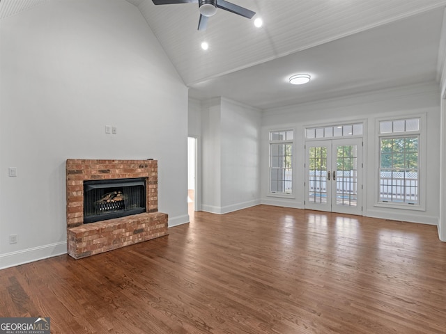 unfurnished living room featuring french doors, a brick fireplace, wood finished floors, high vaulted ceiling, and baseboards