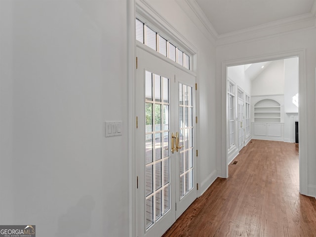 entryway with a fireplace, wood finished floors, baseboards, built in features, and ornamental molding