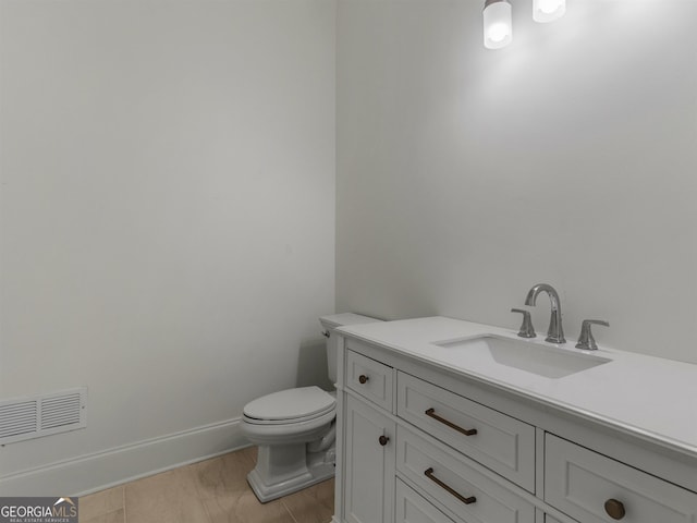 bathroom featuring toilet, vanity, visible vents, and baseboards