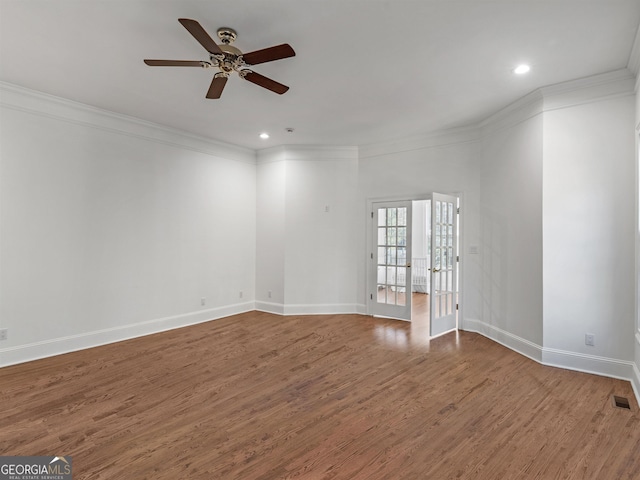 spare room with ornamental molding, visible vents, baseboards, and wood finished floors