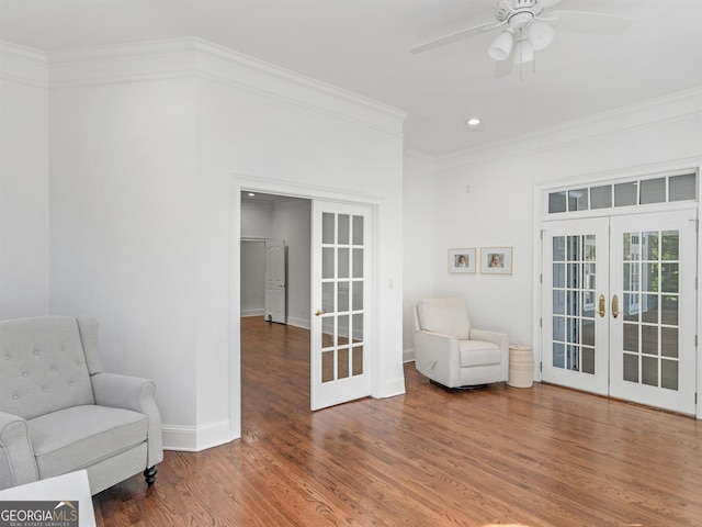 sitting room with baseboards, ceiling fan, wood finished floors, crown molding, and french doors