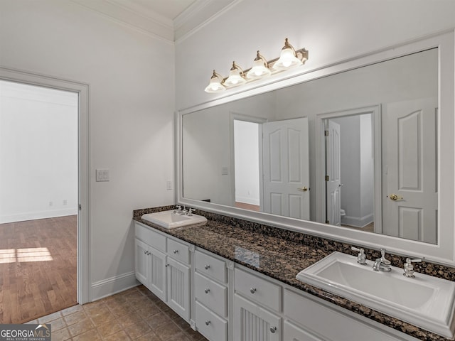 bathroom with ornamental molding, a sink, toilet, and double vanity