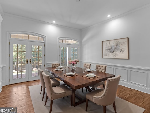 dining space featuring light wood-style floors, ornamental molding, and french doors