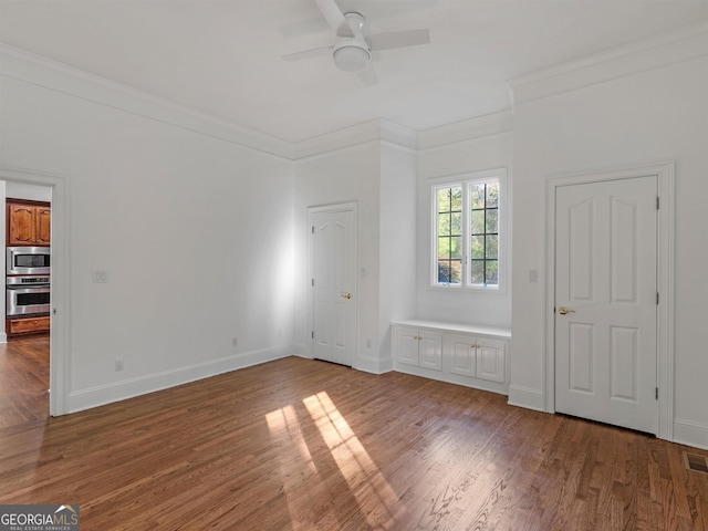 unfurnished bedroom with ornamental molding, wood finished floors, a ceiling fan, and baseboards