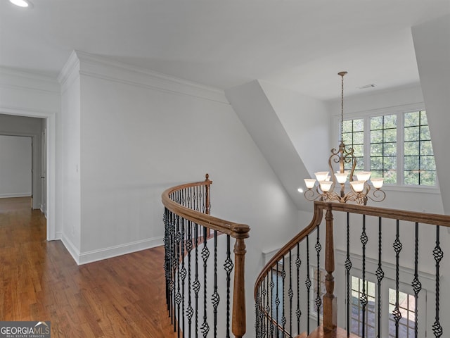 stairway featuring a chandelier, ornamental molding, baseboards, and wood finished floors