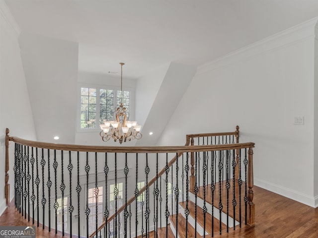 hallway with a chandelier, wood finished floors, an upstairs landing, baseboards, and crown molding