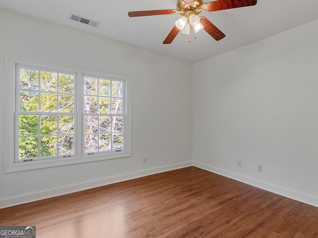 empty room with baseboards, visible vents, ceiling fan, and wood finished floors