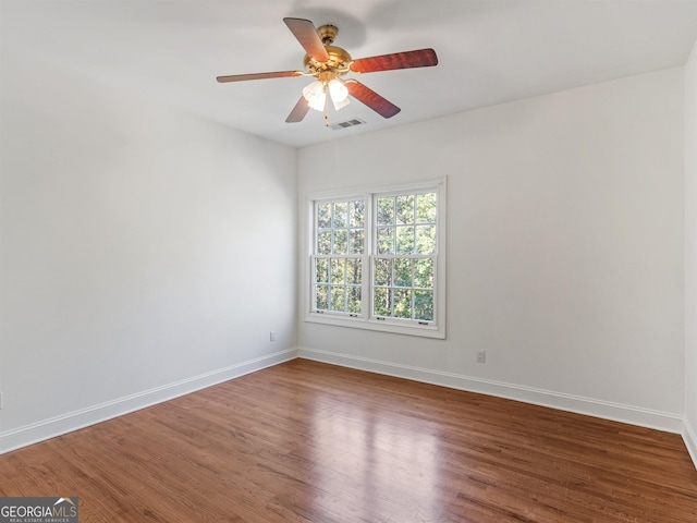 empty room with visible vents, ceiling fan, baseboards, and wood finished floors