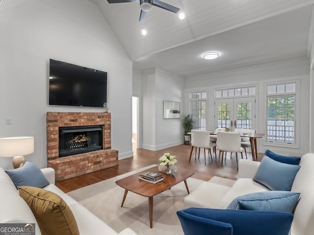 living room with baseboards, wood finished floors, french doors, a brick fireplace, and high vaulted ceiling