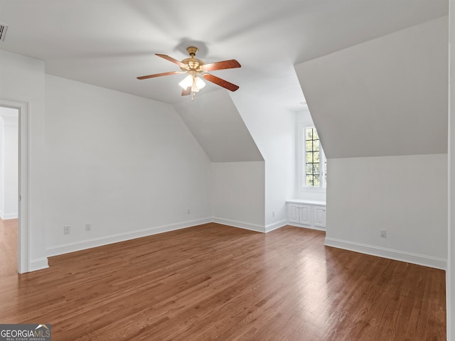 bonus room with wood finished floors, visible vents, a ceiling fan, vaulted ceiling, and baseboards