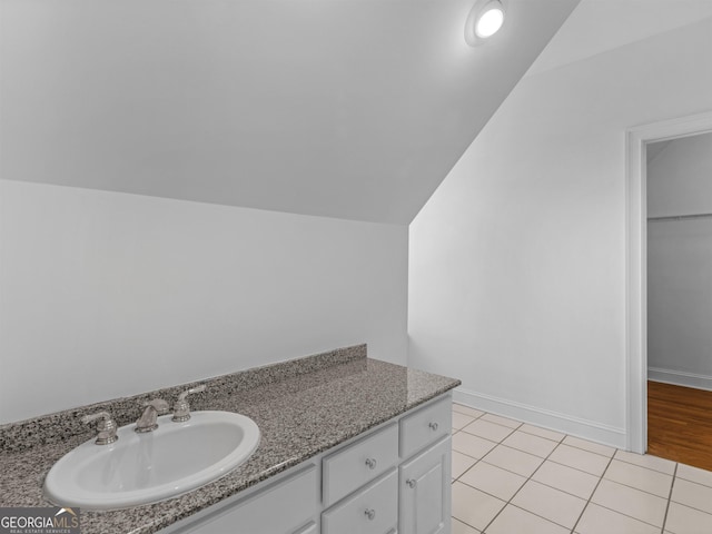 bathroom featuring lofted ceiling, baseboards, vanity, and tile patterned floors