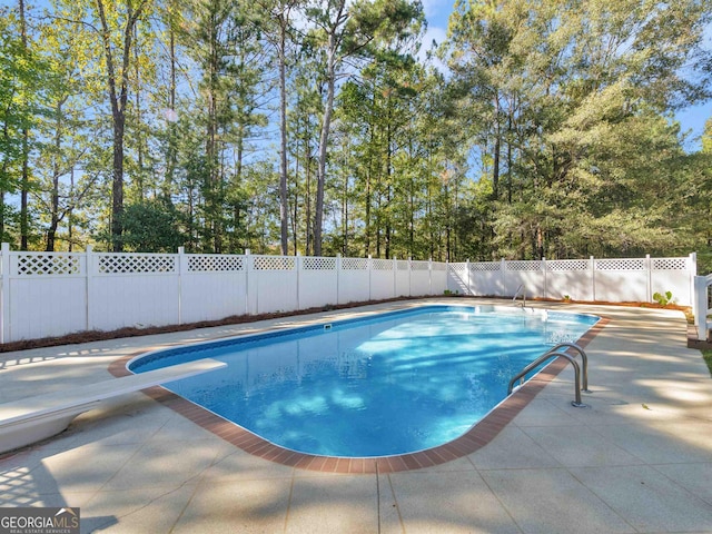 view of pool with a fenced backyard, a patio, and a diving board