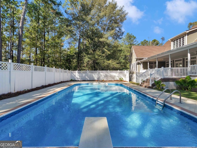 view of swimming pool with a wooden deck, a diving board, a fenced backyard, and a fenced in pool