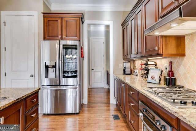 kitchen featuring under cabinet range hood, ornamental molding, stainless steel appliances, and light wood finished floors