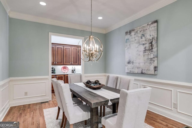 dining room featuring recessed lighting, a notable chandelier, light wood-style floors, wainscoting, and crown molding