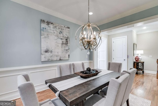 dining room with wainscoting, a chandelier, crown molding, and wood finished floors