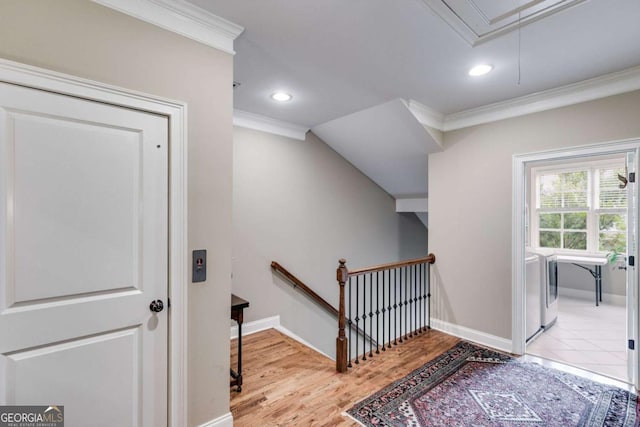 hall with attic access, baseboards, ornamental molding, wood finished floors, and an upstairs landing