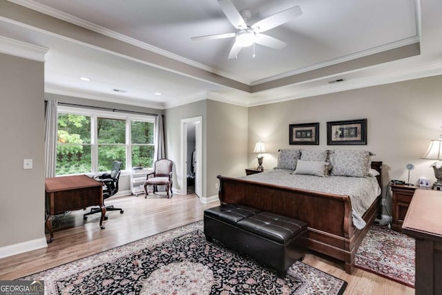 bedroom featuring crown molding, baseboards, a raised ceiling, and wood finished floors