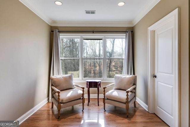 sitting room with baseboards, visible vents, and ornamental molding