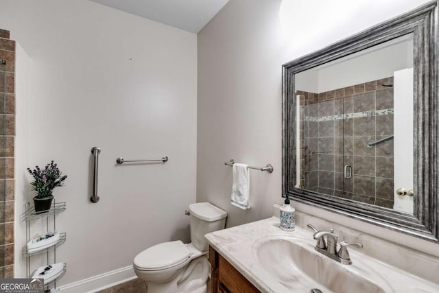 full bathroom with vanity, a shower stall, toilet, and baseboards