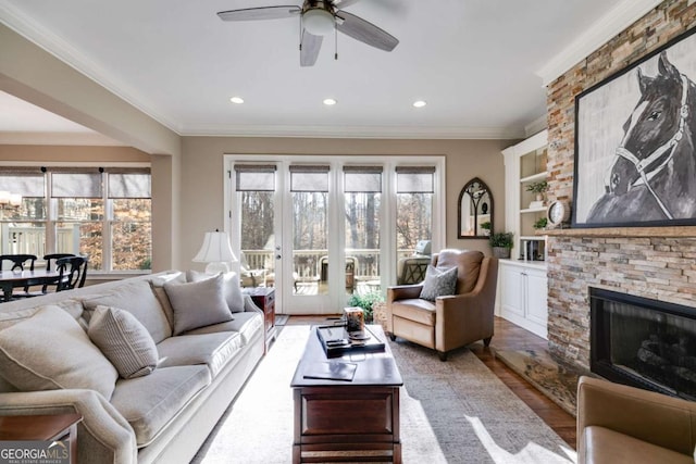 living room featuring recessed lighting, a fireplace, wood finished floors, and crown molding