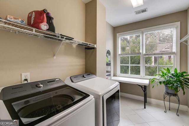 clothes washing area featuring laundry area, washer and clothes dryer, visible vents, and baseboards