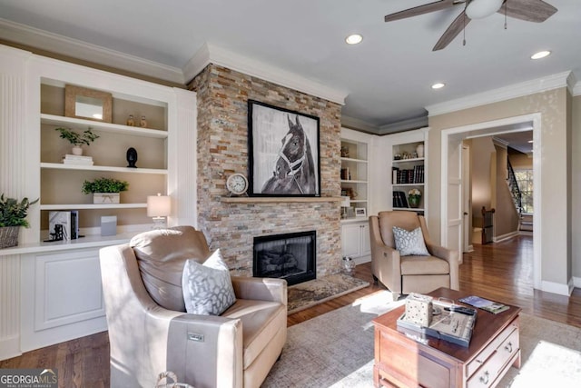 living area with dark wood-type flooring, crown molding, a stone fireplace, and baseboards