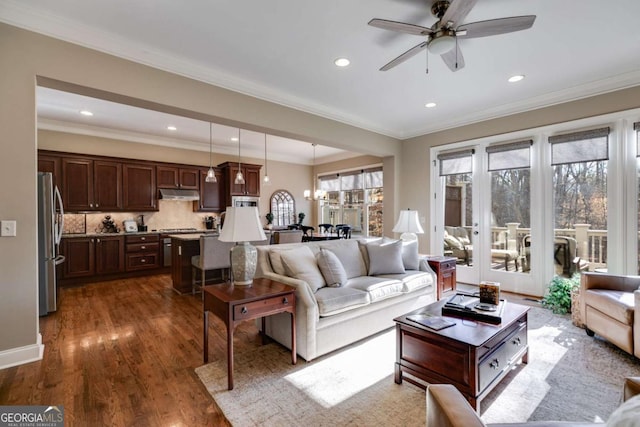 living area with a ceiling fan, ornamental molding, dark wood-type flooring, and recessed lighting