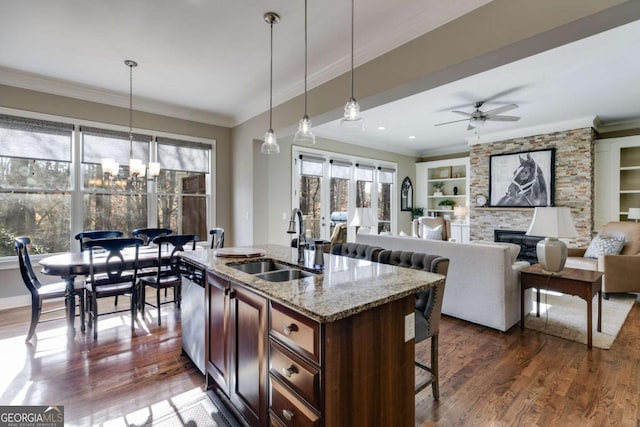 kitchen with a fireplace, a wealth of natural light, stainless steel dishwasher, a sink, and a kitchen breakfast bar