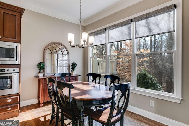 dining space featuring ornamental molding, light wood-style floors, and baseboards