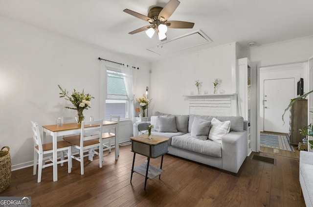 living room with attic access, baseboards, hardwood / wood-style floors, and a ceiling fan