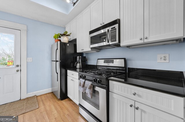 818 Virgil St NE, Atlanta, GA 30307 - kitchen featuring appliances with stainless steel finishes, dark countertops, light wood-style flooring, and white cabinets