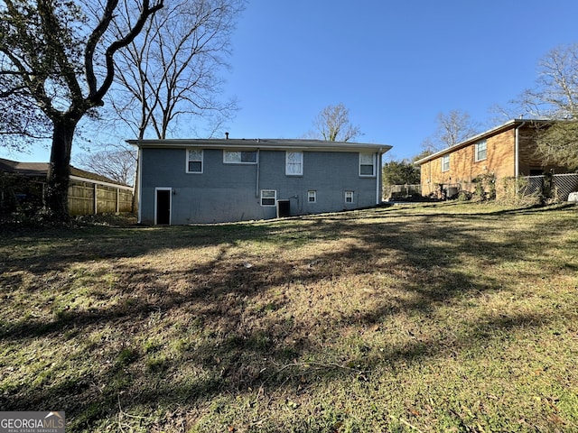 back of property featuring a yard, brick siding, and fence