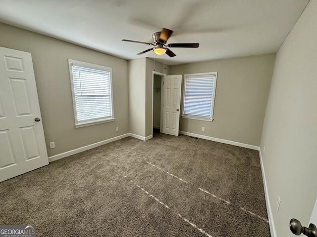 unfurnished bedroom with carpet floors, multiple windows, and baseboards