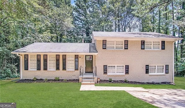 tri-level home featuring brick siding and a front yard