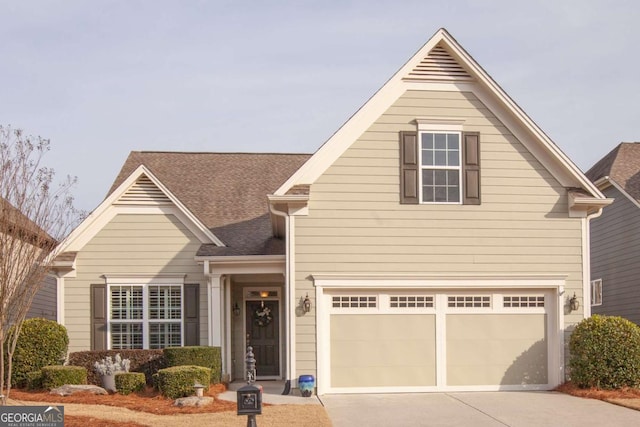 traditional home with roof with shingles, driveway, and an attached garage