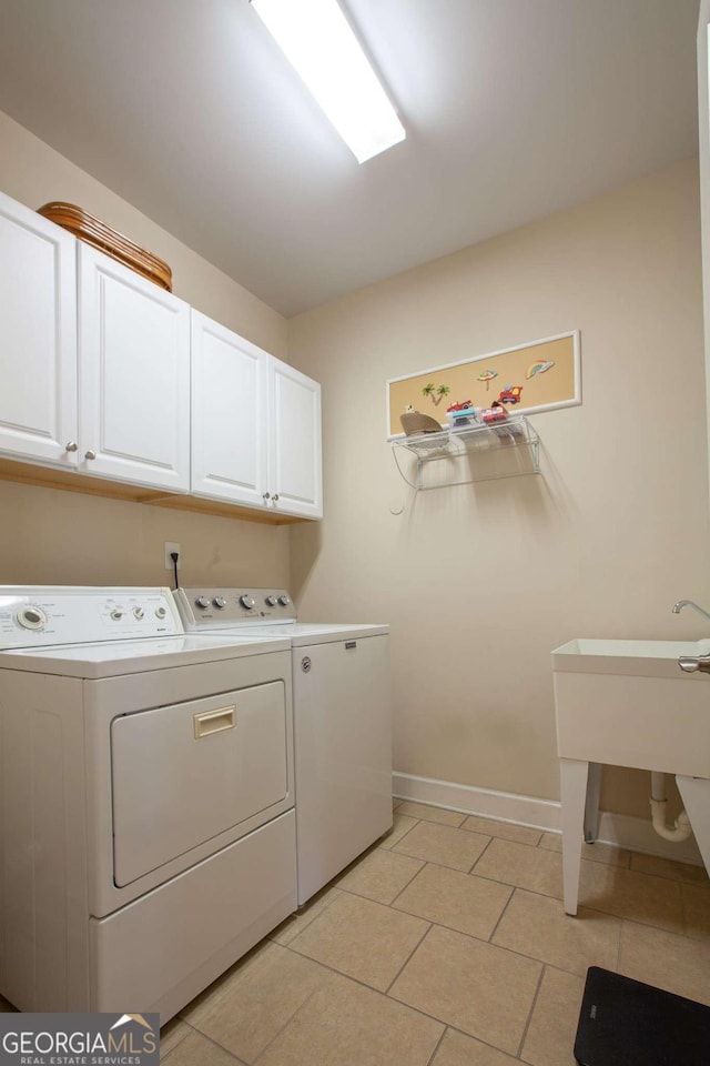 washroom with washing machine and dryer, cabinet space, baseboards, and light tile patterned floors