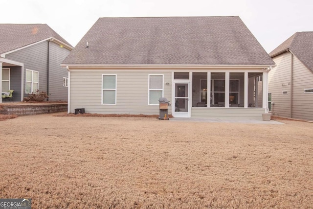 rear view of property with a sunroom and roof with shingles