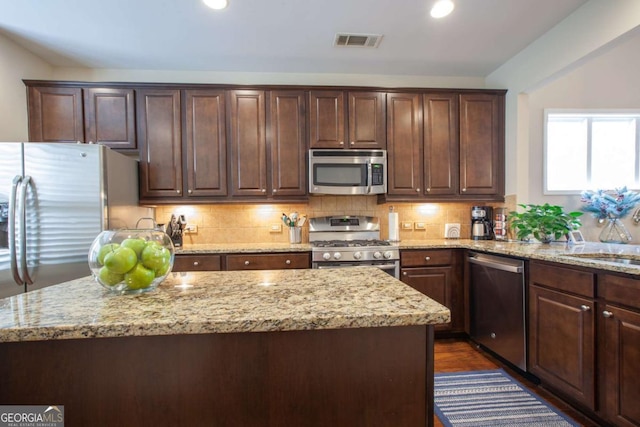 kitchen with stainless steel appliances, visible vents, light stone counters, and decorative backsplash