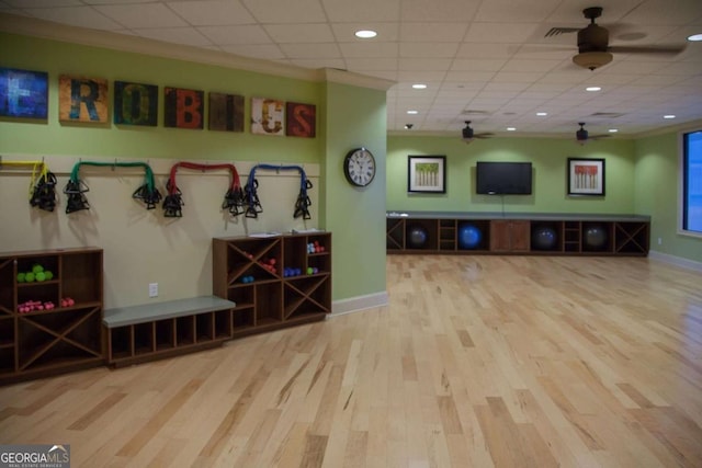 interior space with a ceiling fan, a drop ceiling, baseboards, and wood finished floors